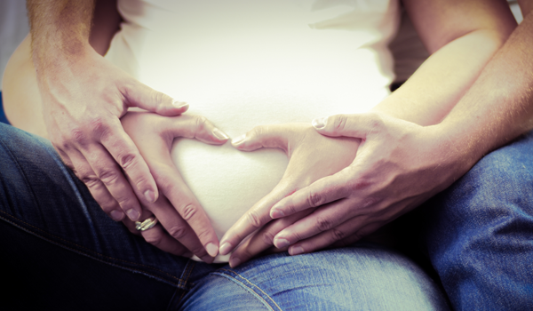 a pregnant couple sitting on a bed